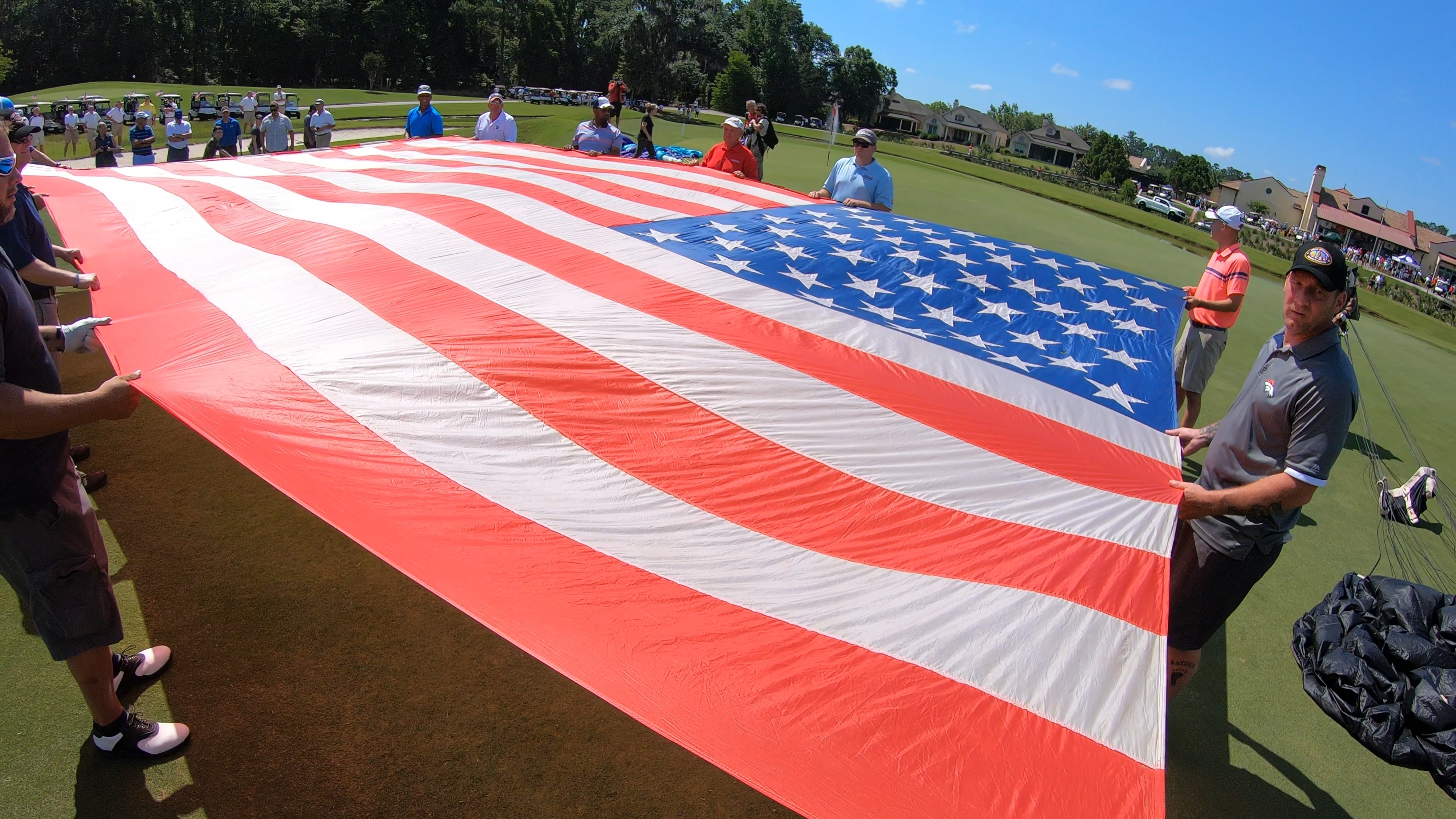 Crowd holding a massive American flag on the green
